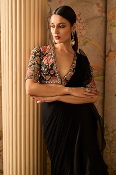 Elevate your style with this exquisite black raw silk embroidered blouse featuring stunning mirror embellishments. Paired with a chiffon drape sari adorned with an organza ruffle, this ensemble exudes sophistication and timeless beauty, making it perfect for special occasions and celebrations. Black Saree Blouse Designs, Drape Sari, Black Saree Blouse, Black Blouse Designs, Saree Chiffon, Ridhi Mehra, Organza Blouse, Drape Saree, Saree Blouse Designs Latest