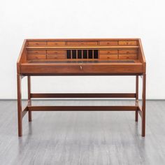 a wooden desk sitting on top of a hard wood floor next to a white wall