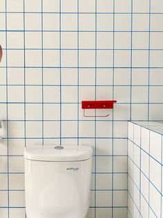 a white toilet sitting in a bathroom next to blue and white tiled walls with red accents