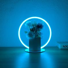 a vase filled with flowers sitting on top of a table next to a blue light