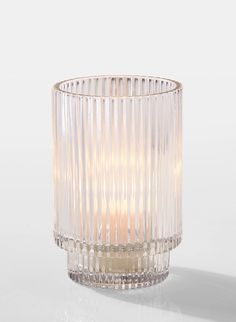 a clear glass candle holder sitting on top of a table