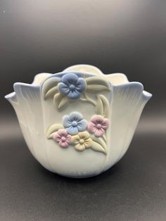 a white bowl with flowers painted on the front and sides, sitting on a table