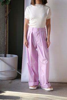 Sale items are final sale. No returns or exchanges. Expertly crafted from soft cotton, these pleated lilac pants feature a high rise and double pleats, providing both comfort and style. The white button fastening closure and belt loops add functional details, while the side slip pockets and back buttoned pockets add a touch of practicality. Perfect for any occasion. Need further assistance? Text our stylists for more details about fit, fabrication, photos etc! Relaxed fit, we suggest ordering a Purple Cotton Bottoms With Belt Loops, Lavender Wide Leg Cotton Bottoms, Purple Pleated Bottoms For Spring, High-waist Lavender Pants For Spring, Lavender Cotton Bottoms Relaxed Fit, Lavender Cotton Bottoms With Relaxed Fit, Relaxed Fit Lavender Cotton Bottoms, Lavender Bottoms For Spring Workwear, Chic Lavender Pants For Spring