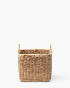 a wicker basket with two handles on the front and side, against a white background