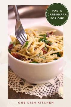 a white bowl filled with pasta sitting on top of a table next to a fork