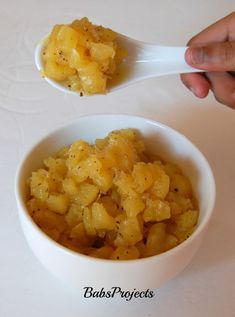 two bowls filled with food on top of a white table next to each other and one is holding a spoon