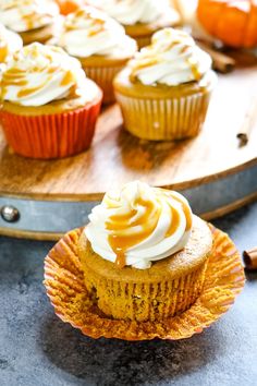 cupcakes with frosting and cinnamon on a wooden tray next to other cupcakes