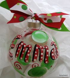 a glass ornament with a red and green polka dot ribbon