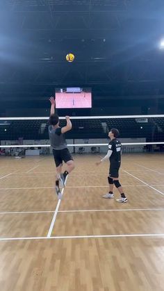 two men are playing tennis on an indoor court