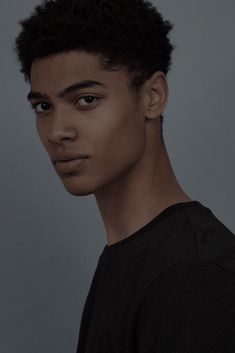 a young man with black hair is looking at the camera while wearing a black t - shirt