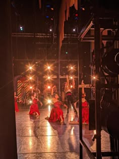 several people are dancing on stage with their lights on