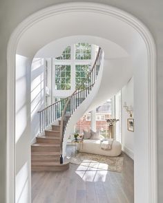 an archway leading to a living room with white walls and hardwood floors, along with a staircase that leads up to the second floor