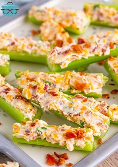 several green peppers topped with cheese and bacon on a white platter next to glasses