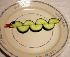 a piece of cucumber on a plate with a toothpick in the shape of a caterpillar