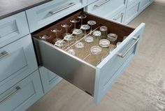 an open drawer in a kitchen filled with glasses