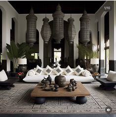 a living room filled with white couches and black tables in front of large chandeliers