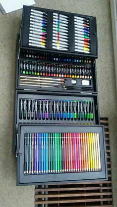 an assortment of colored pencils and markers in a black case on the floor next to a window