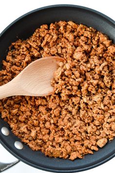 a wooden spoon in a skillet filled with ground meat