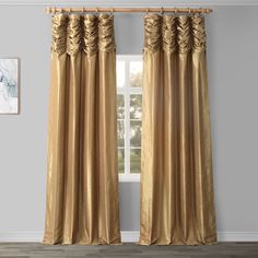 gold curtains with ruffles on them in front of a white wall and wooden floor