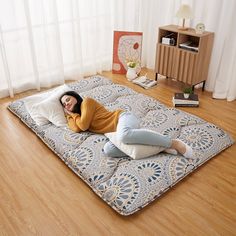 a woman laying on top of a blue and white mattress