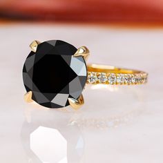 a black diamond ring sitting on top of a white surface with gold trimmings