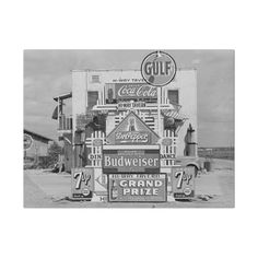 a black and white photo of an old gas station with signs on it's side