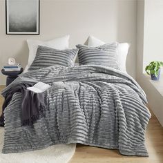 a bed covered in grey and white blankets