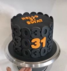 a black and orange birthday cake with the number thirteen on it's side being held up by a hand