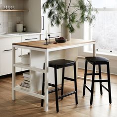 two stools sit at the center of a kitchen island in front of an open window