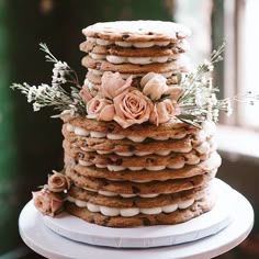 a tall stack of cookies sitting on top of a white cake plate covered in frosting