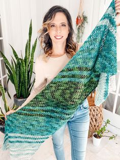 a woman holding up a green and blue shawl