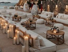 an outdoor seating area with candles lit on the tables and couches in front of it