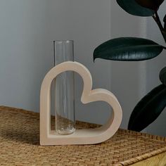 a heart shaped vase sitting on top of a wooden table next to a glass bottle