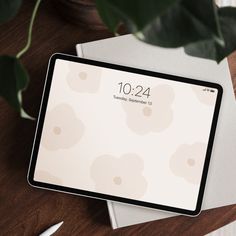 an ipad sitting on top of a wooden table next to a white envelope and pen