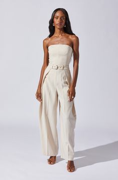 Tailored pleat jumpsuit with belt Boning around bust Concealed back zipper closure Functional side pockets Partially lined Dry clean only 100% Polyester Style #ACP7342 Bridal Brunch Outfit, White Bridal Jumpsuit, Neutral Jumpsuit, Jumpsuit Outfit Wedding, Engagement Party Outfit, Beige Jumpsuit, Jumpsuit With Belt, Recruitment Outfits, Jumpsuit Outfits