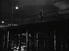 a man standing on top of a bridge at night