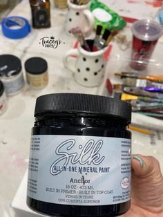 someone holding up a jar of black acrylic paint