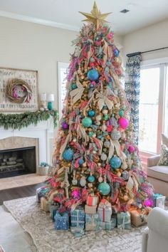 a decorated christmas tree in a living room with blue and pink ornaments on the top