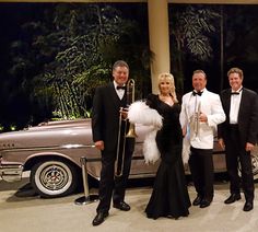 a group of people standing next to each other in front of a car with an instrument