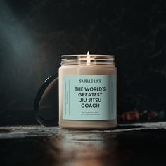 a candle sitting on top of a wooden table next to a cup filled with liquid