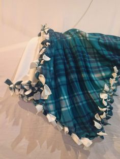 a blue and white plaid blanket laying on top of a bed with ruffled edges