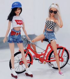 two dolls are posed next to each other on a bike with the same outfit and hat