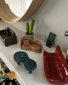 various items are displayed on a shelf in a room with a round mirror above it