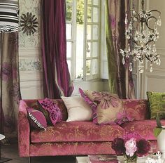 a living room filled with furniture and lots of pink flowers in vases on the coffee table