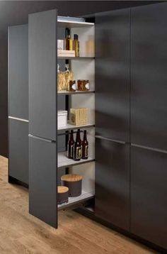 an open cabinet in a kitchen with lots of bottles on the bottom shelf and shelves below it