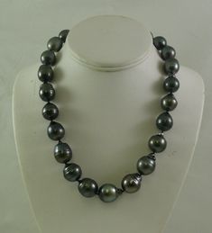 SKU # = 0471 Tahitian Pearl Necklace Pearl Size Range = 14.0 x 17.9 mm - 16.5 x 20.7 mm Number of Pearls = 23 Pearls Color of Pearls = Black with Dark Gray and slight pink tint Shape of Pearls = Baroque Gold = 14k White Gold Clasp Necklace Length including clasp = 19 inches Tahitian Pearls: These pearls are among the rarest of all pearls that are available found off the seas of Tahiti. Tahitian Pearls are natural color pearls that are very rare. They come in colors including black, gray, and gre Black Pearl Necklace With High Luster For Gift, Tahitian Pearl Necklace, Pear Shaped Ring, Black Pearl Necklace, Freshwater Pearl Ring, Gold Rings Jewelry, Pearl Jewelry Necklace, Baroque Pearl Necklace, Clasp Necklace