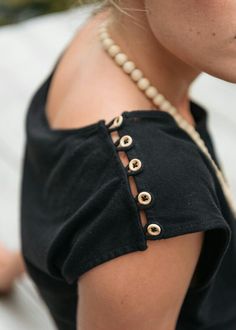 a close up of a woman wearing a black shirt and pearls on her neckline