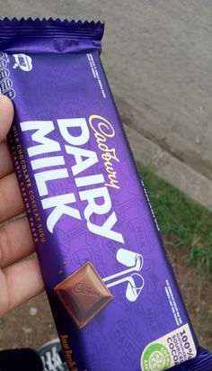 a hand holding a bar of dairy milk chocolate