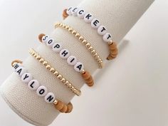 one name bracelet made with 6mm sandalwood beads and 14k gold spacer beads bracelets are made on a durable stretch elastic cord please refer to our sizing guide before purchasing Clay Bead Jewelry, Rainbow Writing, Gold Writing, Bracelet Inspo, Wooden Names, Beads Bracelets, White Rainbow, Name Bracelet, Spacer Beads