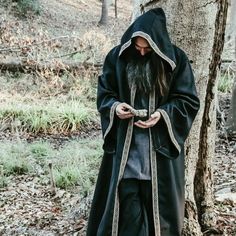 a man dressed in black standing next to a tree